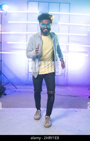 Young man dancing slow motion or robotic moment on stage by looking at camera - concept of entertainment, hobby and professional dancer. Stock Photo