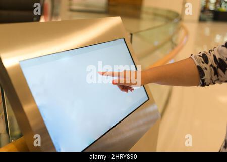 Woman using interactive touchscreen display at urban exhibition - scrolling and touching. Education and technology concept Stock Photo