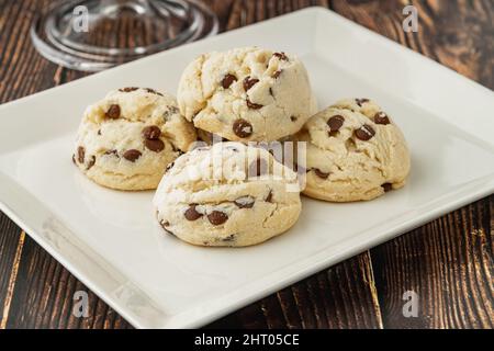 Stacked chocolate chip cookies in white plate on wooden table Stock Photo