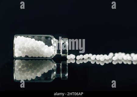 Homeopathic globules scattered out of glass bottle Stock Photo