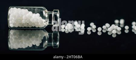 Homeopathic globules scattered out of glass bottle Stock Photo