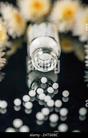 Homeopathic globules scattered out of glass bottle Stock Photo