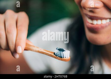 Woman brushing teeth with charcoal Stock Photo