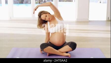Warming up for a workout. Full length shot of an attractive young pregnant woman warming up before a workout. Stock Photo