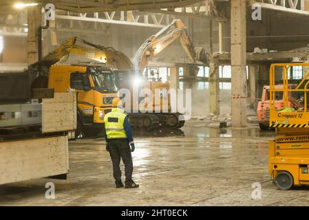 Roznov Czech Rep 4th January 2022 Worker watching heavy machinary and excavator doing construction work inside of an industrial building Stock Photo