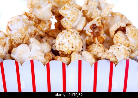 A container of popcorn food close up on a white isolated background. Red striped square carboard box of kettle corn Stock Photo