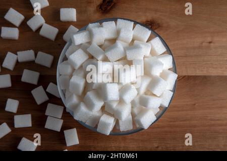 Top view of white sugar cubes in glass bowl full, wooden background Stock Photo