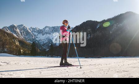 Caucasian female cross country skier stopping and looking at beautiful mountains. Stock Photo