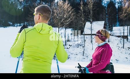 Caucasian couple of recreational cross country skiers, enjoying the beautiful winter mountain scenery while standing on a ski trail. Stock Photo