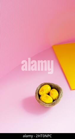 Easter eggs in a natural nest. Painted yellow-golden eggs on a pink background. Easter minimalistic concept. Copy space Stock Photo