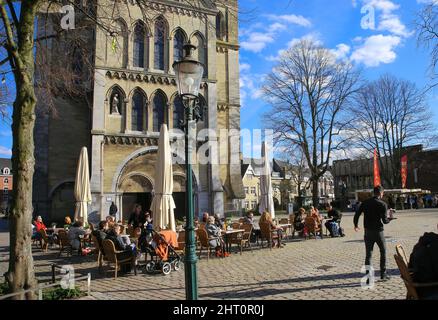 Roermond, Netherlands - February 9. 2022: View over square with people sitting outside cafe in front of medieval church on sunny winter day Stock Photo