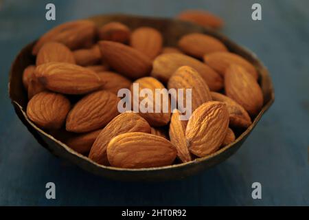 Close-up of  almonds in a copper bowl against blue background Stock Photo