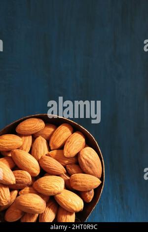 Close-up of  almonds in a copper bowl against blue background Stock Photo
