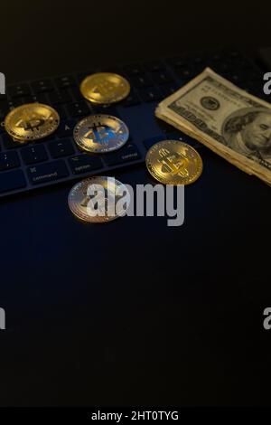 Vertical closeup of the bitcoins and banknotes on the keyboard. Stock Photo