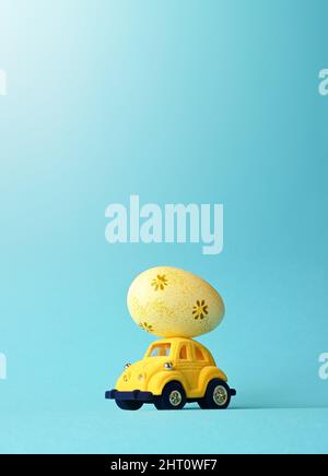 One Easter egg on a small car on a blue background. Copy space. Easter card. Stock Photo