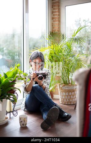Adult woman at home using an analog photo camera. Space for text. Stock Photo
