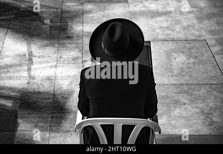 Grayscale of a man sitting on a chair from behind Stock Photo
