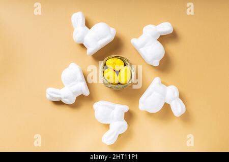 Yellow eggs and easter bunnies. Easter eggs in the nest on a beige background. Easter decoration concept. Top view. Copy space Stock Photo
