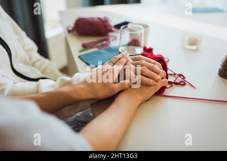 Cropped image of female caregiver stacking hands on senior woman at retirement home Stock Photo