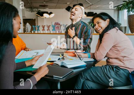 Cheerful university students discussing while enjoying at cafeteria Stock Photo