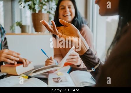 Midsection of young female student discussing with friends at cafeteria Stock Photo