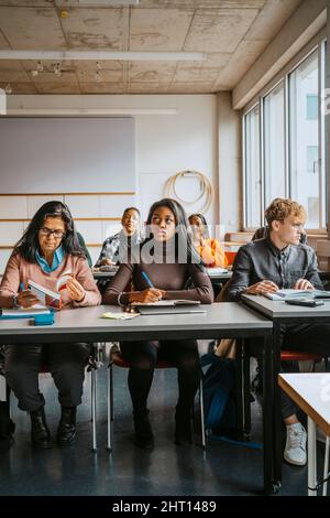 Multiracial university students sitting at desk learning in classroom Stock Photo