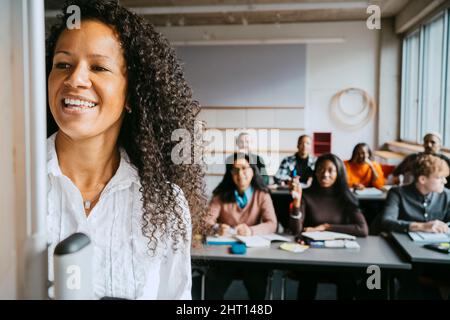 Smiling professor teaching university students in classroom Stock Photo