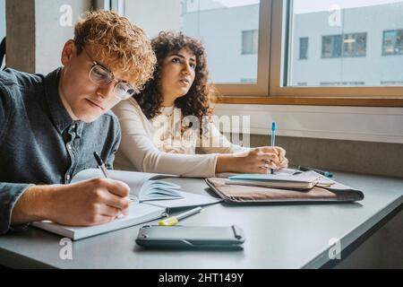 Young multiracial male and female students learning in classroom at community college Stock Photo
