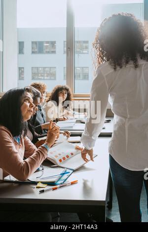 Teacher and students discussing together in classroom at community college Stock Photo