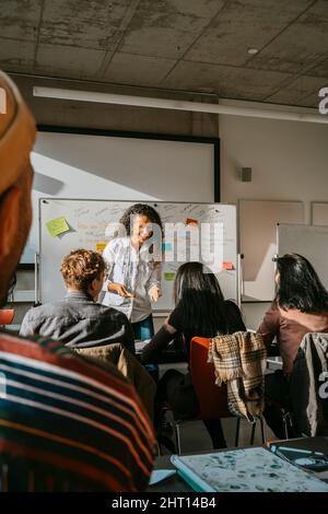 Smiling professor teaching students in classroom at university Stock Photo