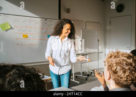 Smiling professor teaching university students in classroom Stock Photo