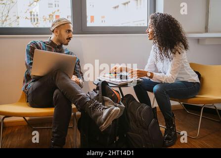 Male and female university students discussing while studying together Stock Photo