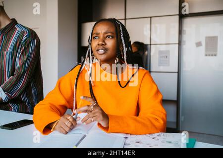 Thoughtful young woman with braided hair sitting at university Stock Photo