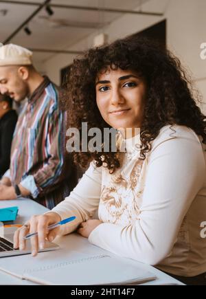 Portrait of young woman with curly hair sitting at community college Stock Photo