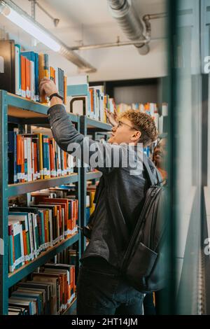 Young students searching book together in library at university Stock Photo