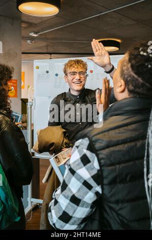 Happy young man giving high-five to female friend in university Stock Photo