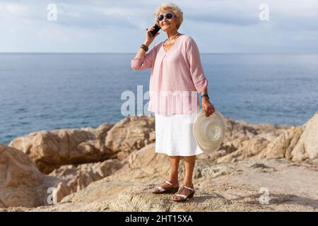 Aged woman talking on phone outdoors Stock Photo