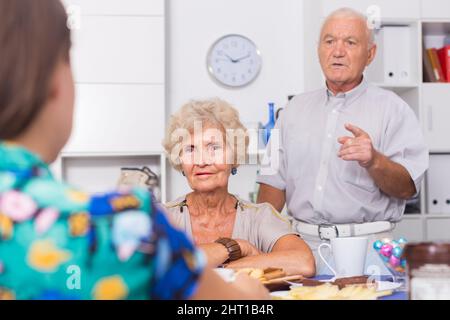 Stressed senior couple having conversation with female Stock Photo