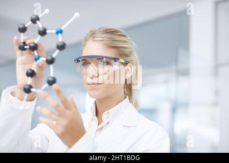 On the brink of a medical break-through. A gorgeous young scientist looking at a molecular structure model. Stock Photo