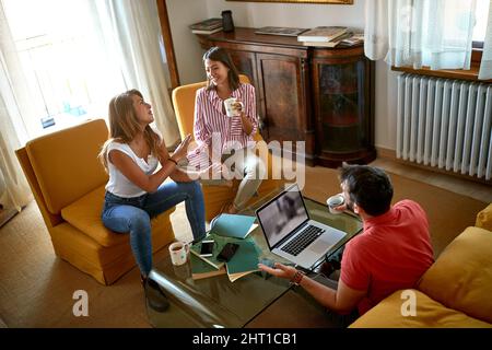 young friends in apartment drink coffee and laugh Stock Photo