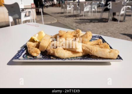 Fried cuttlefish strips, called Chocos Fritos in Spanish. Served on a decorative rectangular plate. Spanish food concept. Stock Photo