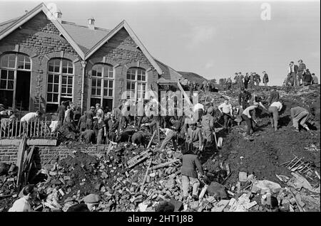 Aberfan, South Wales, circa 21st October 1966 Picture shows the mud and devastation caused when mining spoil from the hillside high above the town behind came down  and engulfed The Pantglas Junior School on 21st October 1966.   Rescuers trying to find victims and help, monist the mud and rubble around the school site.  The Aberfan disaster was a catastrophic collapse of a colliery spoil tip in the Welsh village of Aberfan, near Merthyr Tydfil. It was caused by a build-up of water in the accumulated rock and shale, which suddenly started to slide downhill in the form of slurry and engulfed The Stock Photo