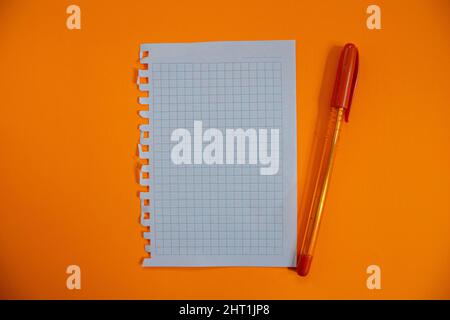 Blank notebook paper and pen isolated on orange background. Top view, flat lay. Stock Photo