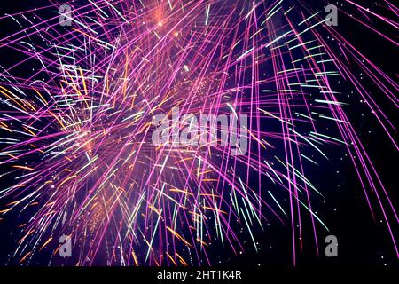 Purple fireworks in a dark sky. Purple festive firecracker.Bright purple, pink and orange firework display in the night sky. Purple and blue fireworks Stock Photo