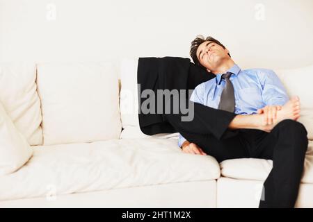 Young business man sleeping on couch at home. Portrait of a young business man sleeping on couch at home. Stock Photo