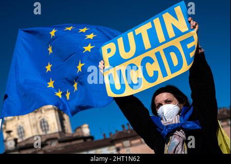 Turin, Italy. 26 February 2022. A demonstrator holds a placard reading 'Putin kills' as an European Union flag is weaving during a protest against Russia's military operation in Ukraine. On 24 February 2022, Russia launched a large-scale invasion of Ukraine. Credit: Nicolò Campo/Alamy Live News Stock Photo