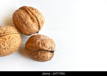 Walnuts (Juglans regia) in shell on white wooden background, close-up, top view. Stock Photo