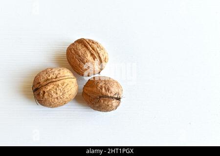 Walnuts (Juglans regia) in shell on white wooden background, close-up, top view. Stock Photo