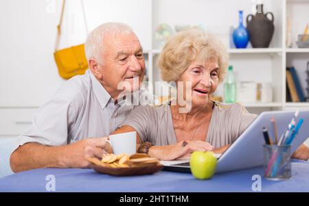 Cheerful mature spouses using laptop at home Stock Photo