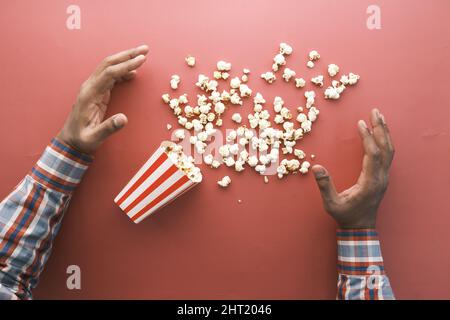 hand reaching for popcorn on red background  Stock Photo